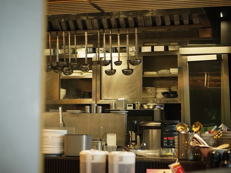 A commercial kitchen line with hanging ladles and stacked plates on the shelves