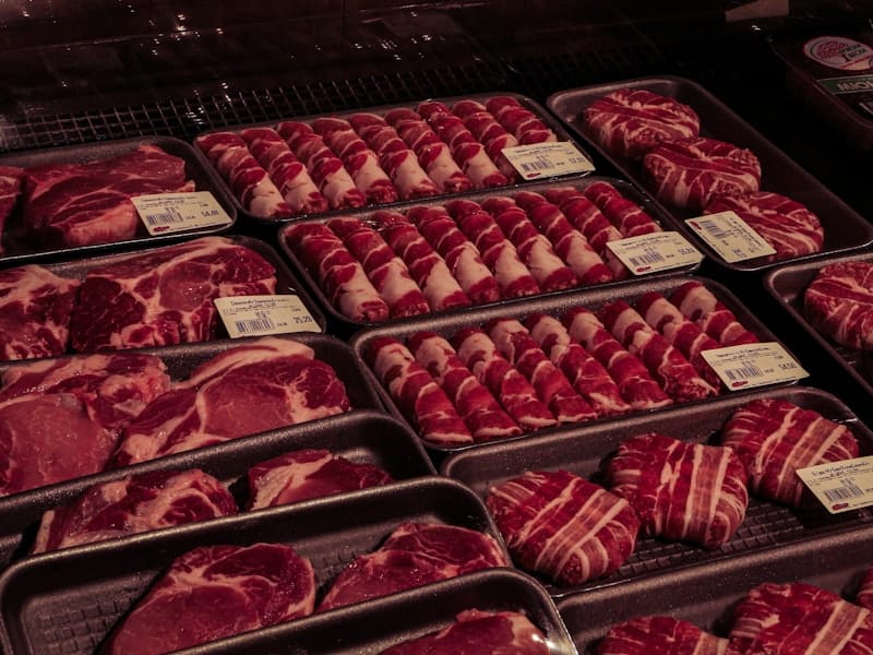 Trays of portioned beef and pork cuts in a refrigerated case