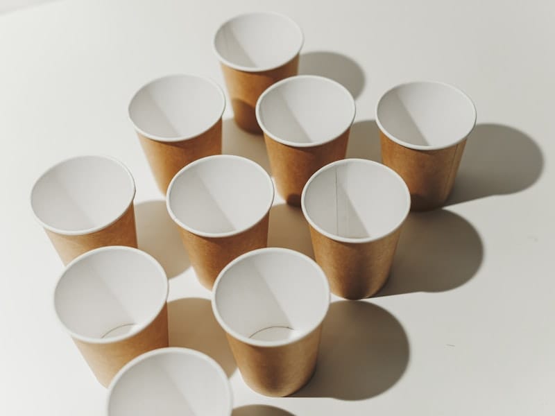 Rows of unused kraft paper cups on a pale surface